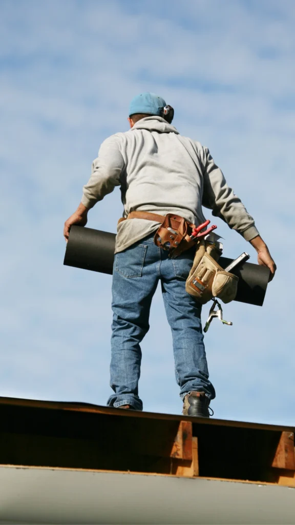 man on a roof carrying materials and tools